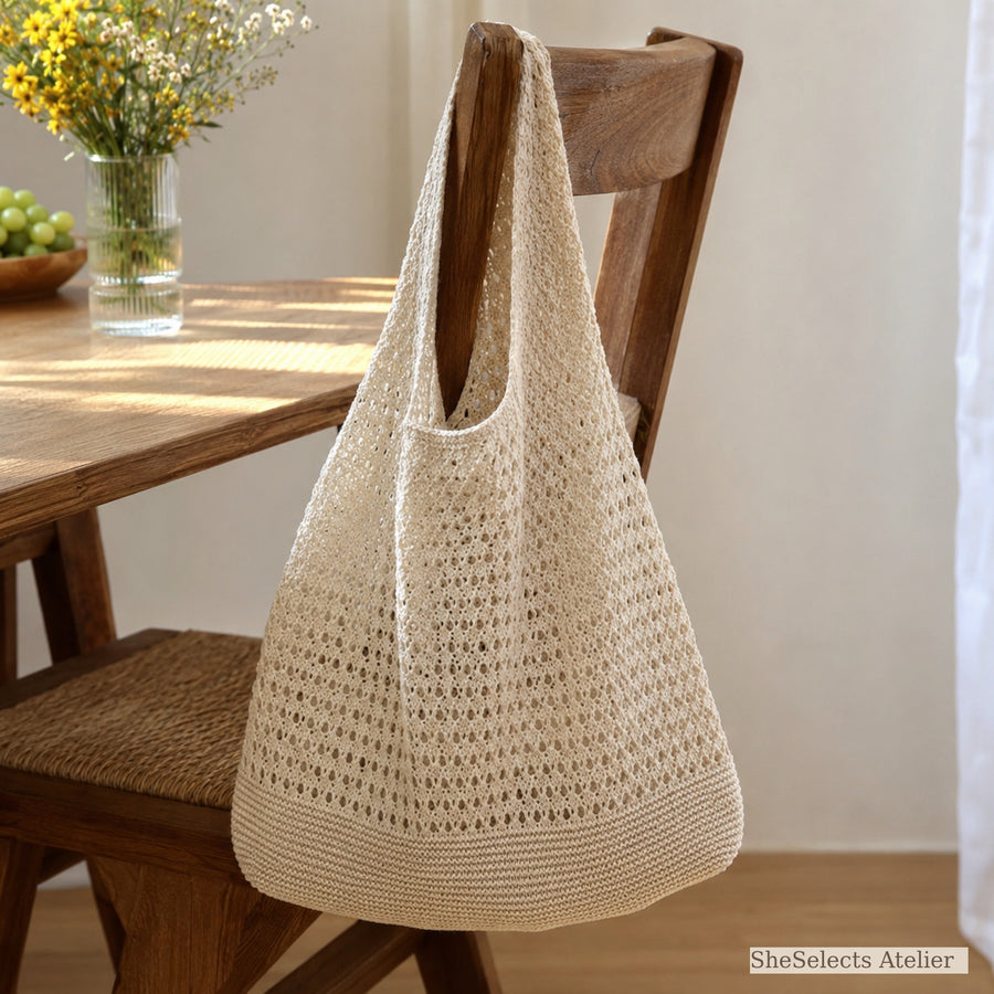 Beige crochet style market bag hanging from a wooden chair