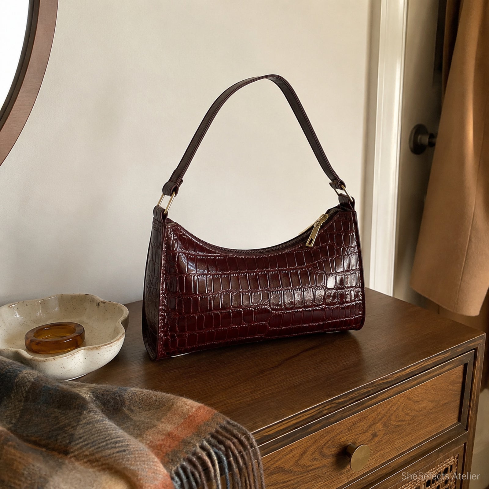 Wine red mini croc embossed shoulder bag on a walnut console in natural home light