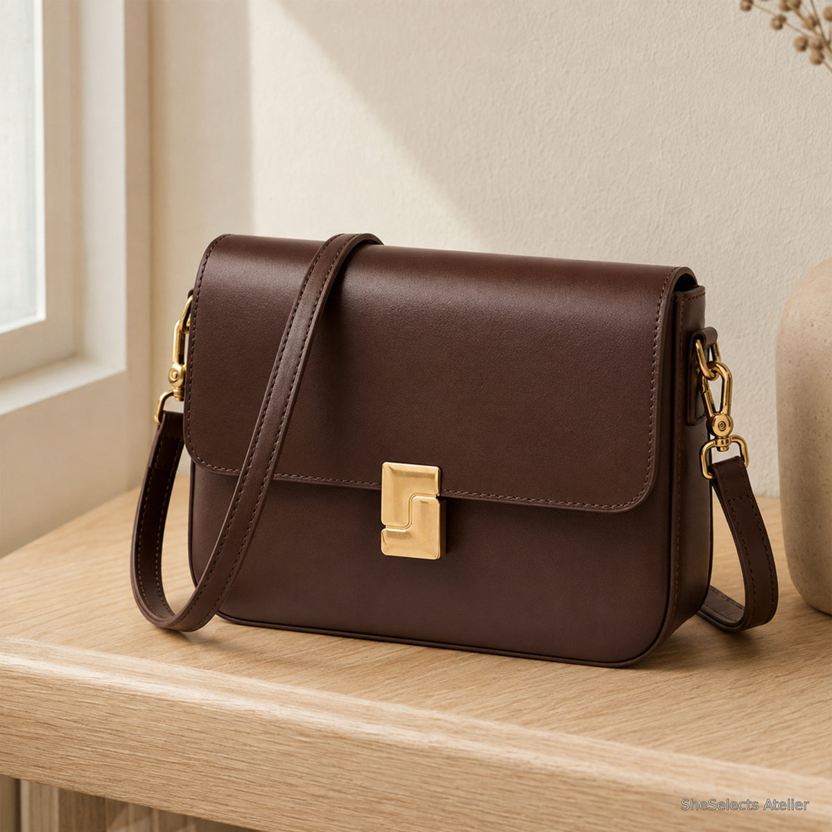 Dark brown genuine leather turn lock crossbody bag on pale oak