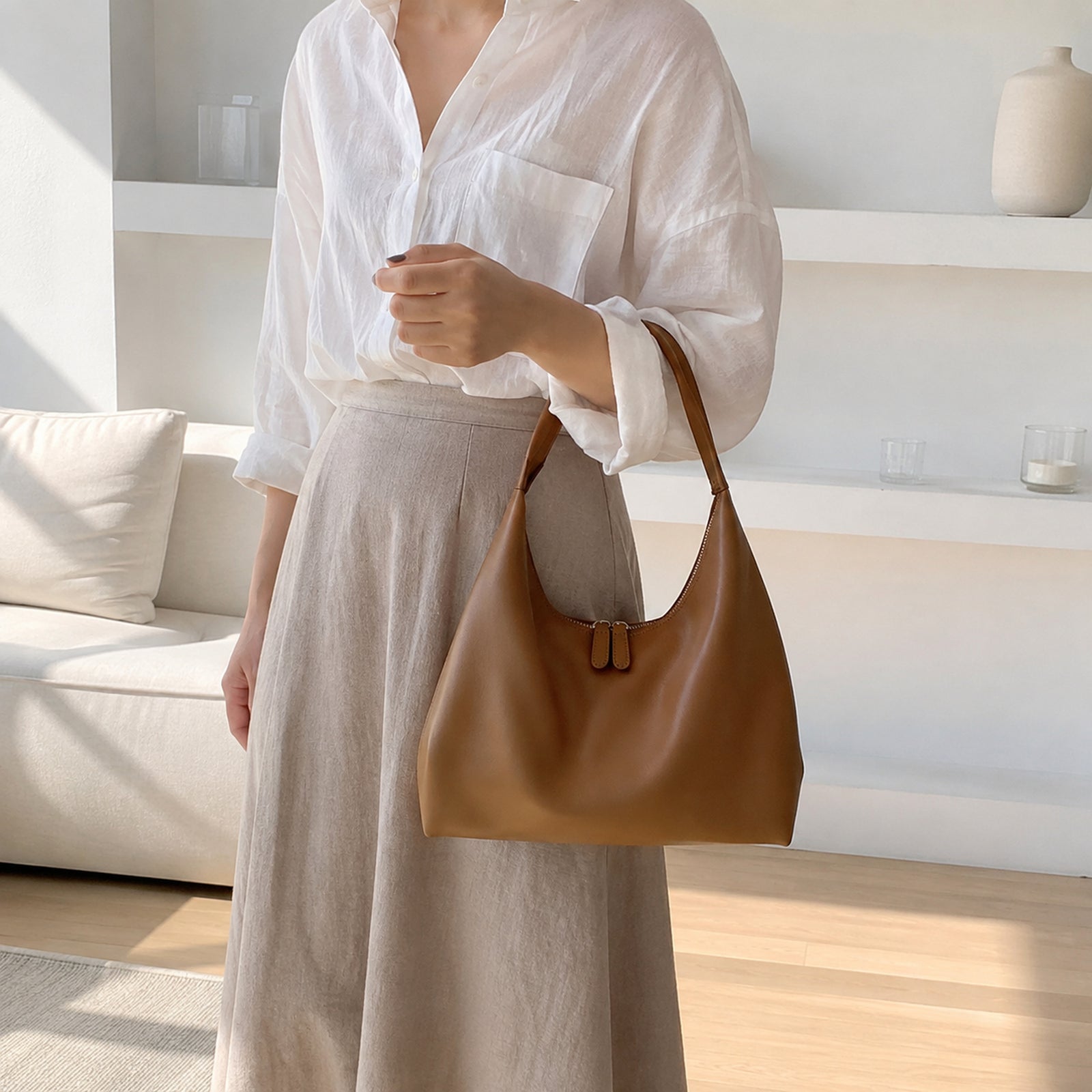 Brown minimalist shoulder purse carried with a white linen blouse and taupe skirt