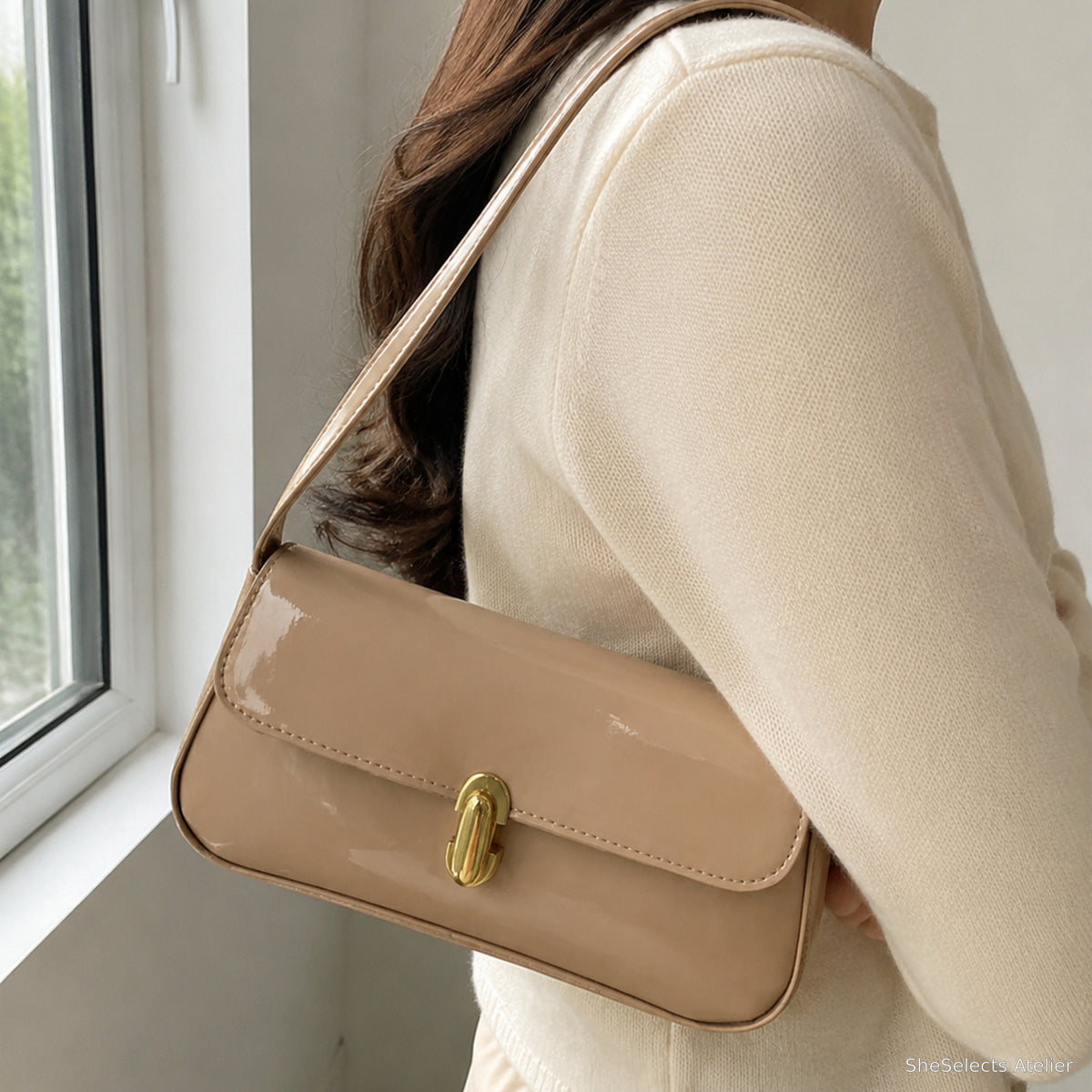 Khaki glossy vegan leather shoulder bag worn beside a window