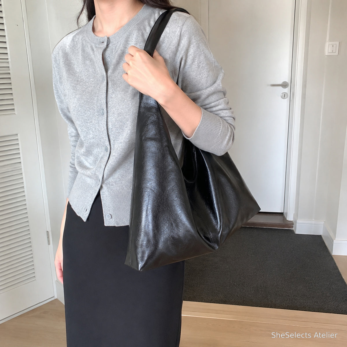 Black slouchy vegan leather shoulder bag worn with a grey cardigan