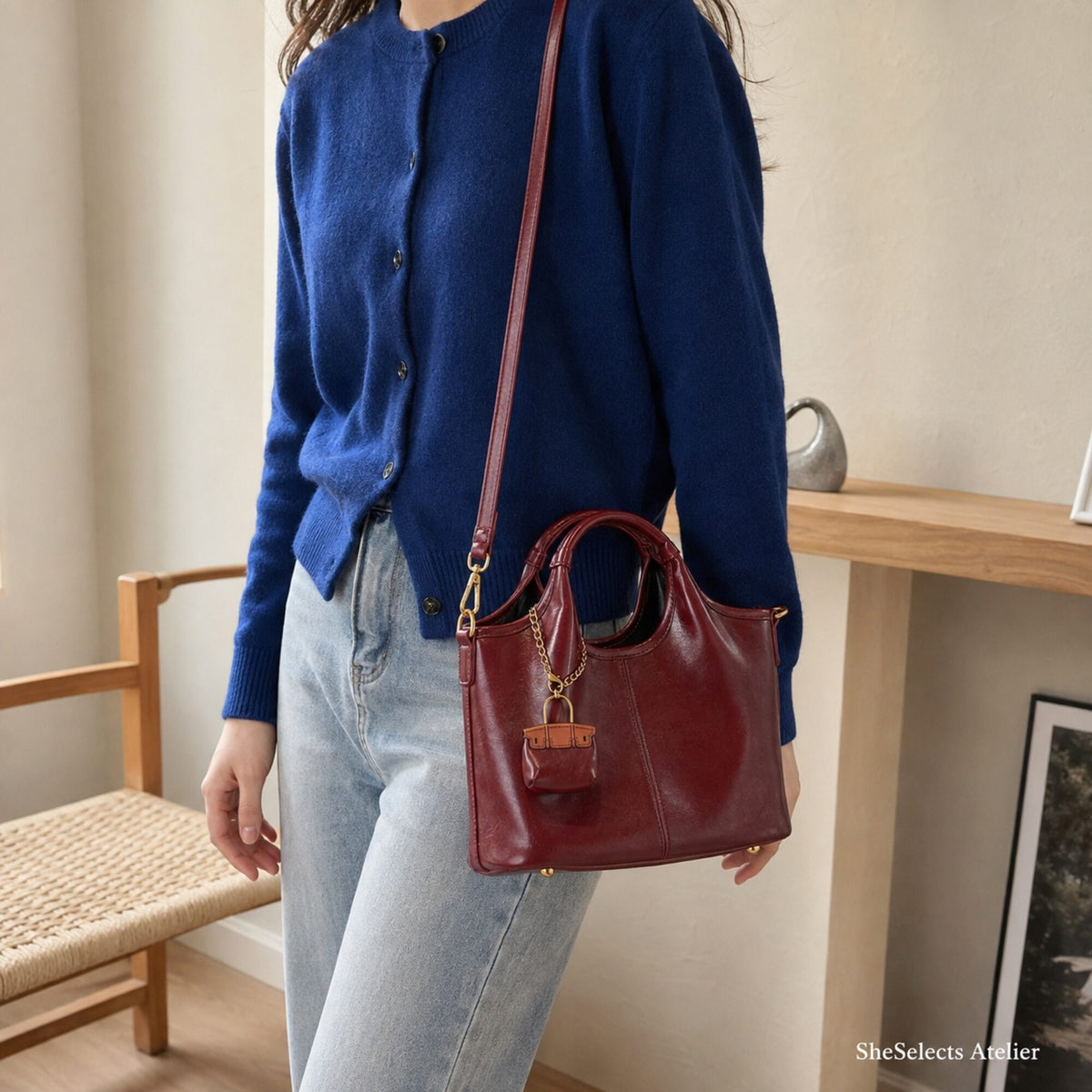 Woman wearing Wine Red vegan leather tote as a crossbody with cobalt cardigan and light denim