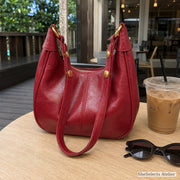 Red vegan leather hobo bag on an outdoor cafe table