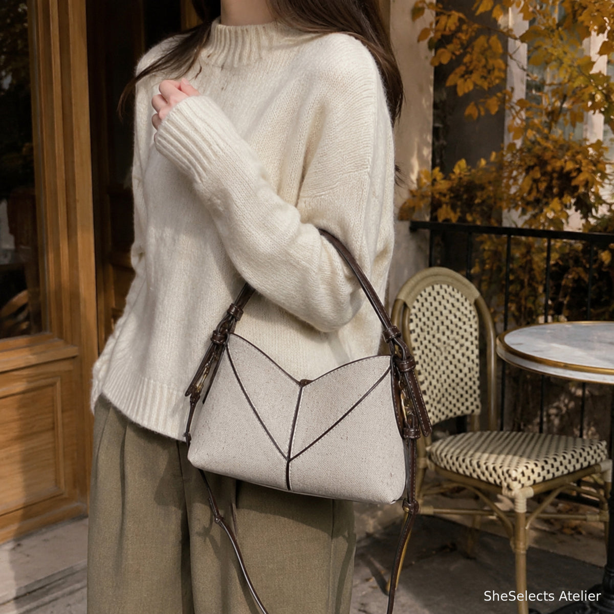 Woman carrying beige canvas hobo shoulder bag at an autumn cafe