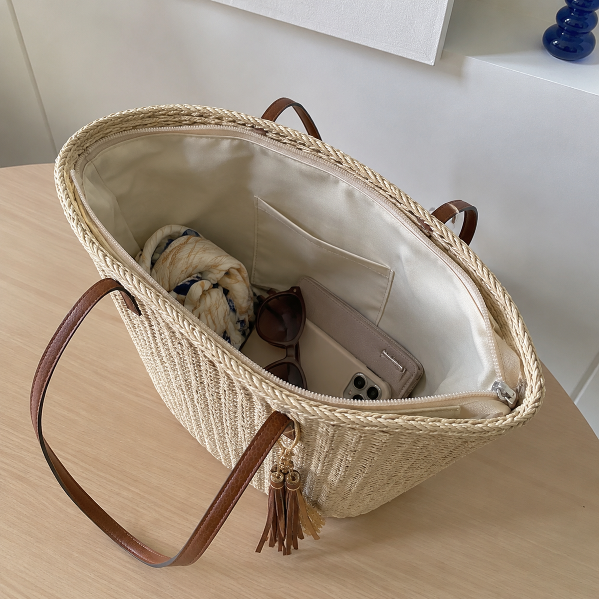 Beige zip-top straw tote opened to show its polyester-lined interior
