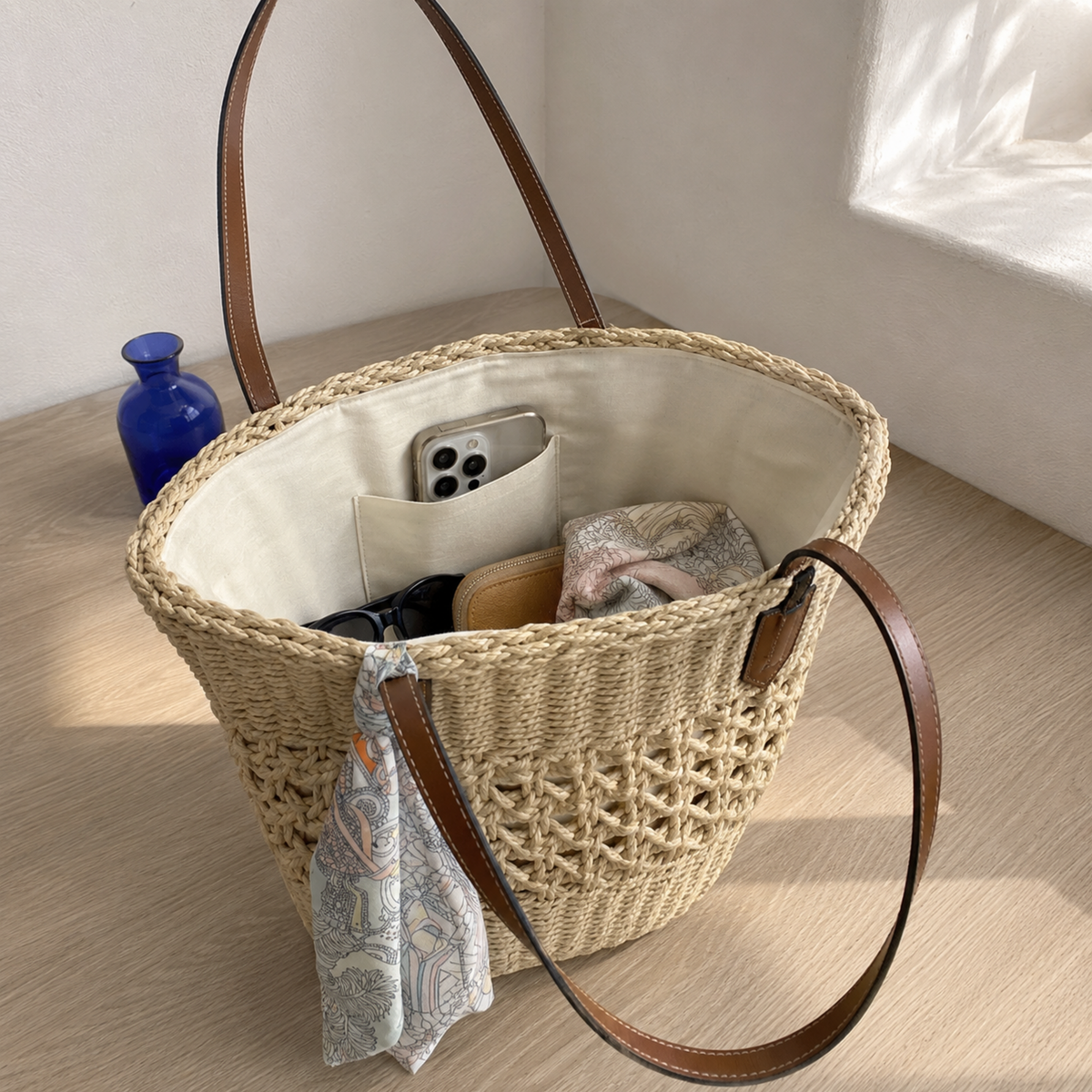 Beige woven straw tote opened to show its polyester-lined phone pocket