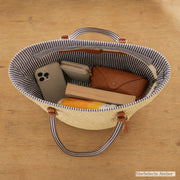 Open beige straw tote showing striped lining and everyday capacity