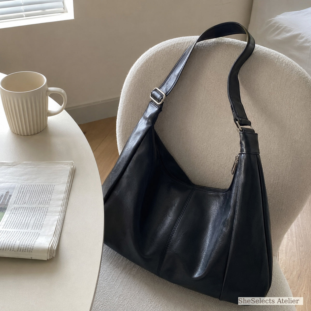 Black vintage hobo bag on a cream chair in a bright home