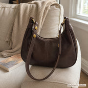 Dark brown soft shoulder bag styled on a neutral sofa