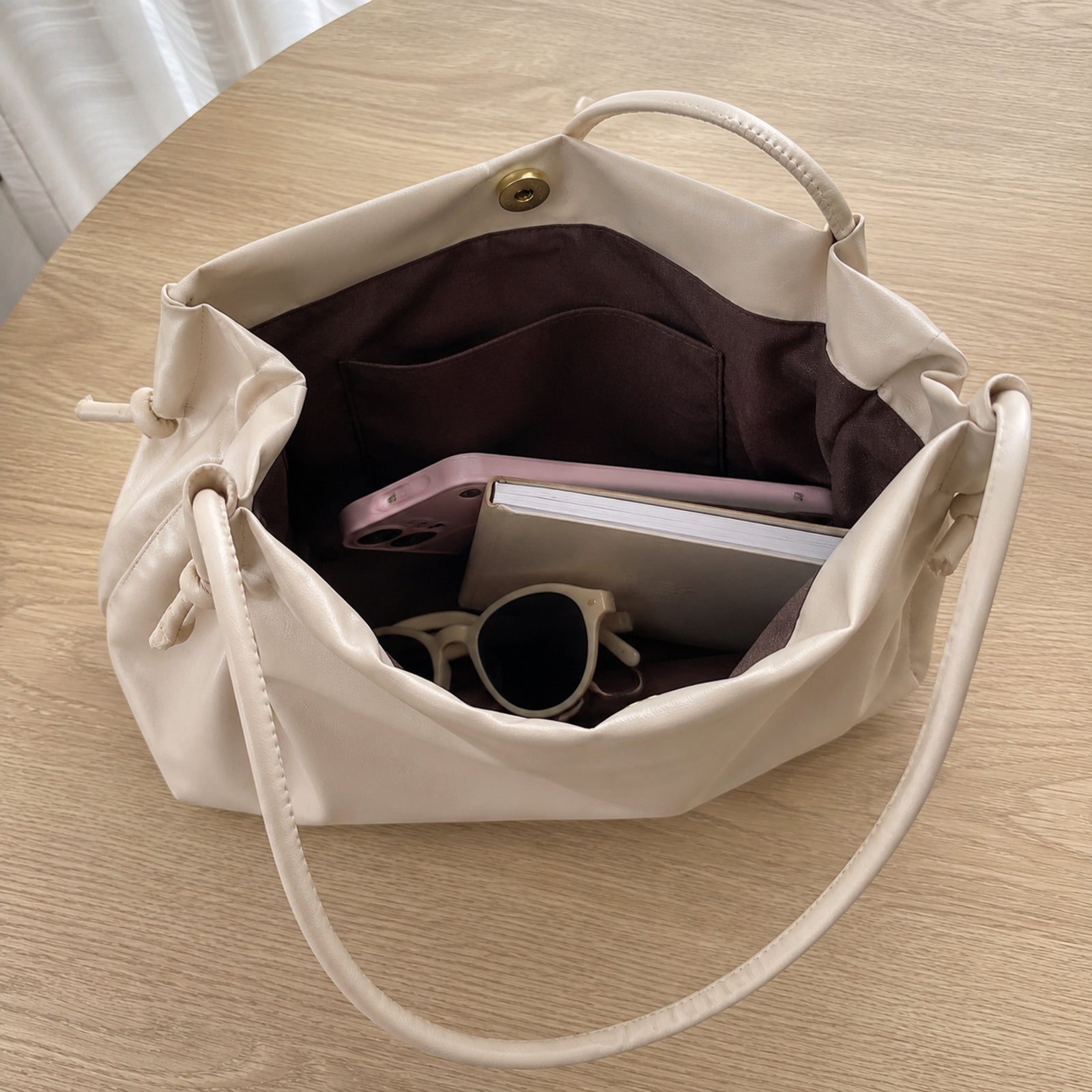 Open beige tote showing dark polyester lining, roomy compartment, and interior pocket