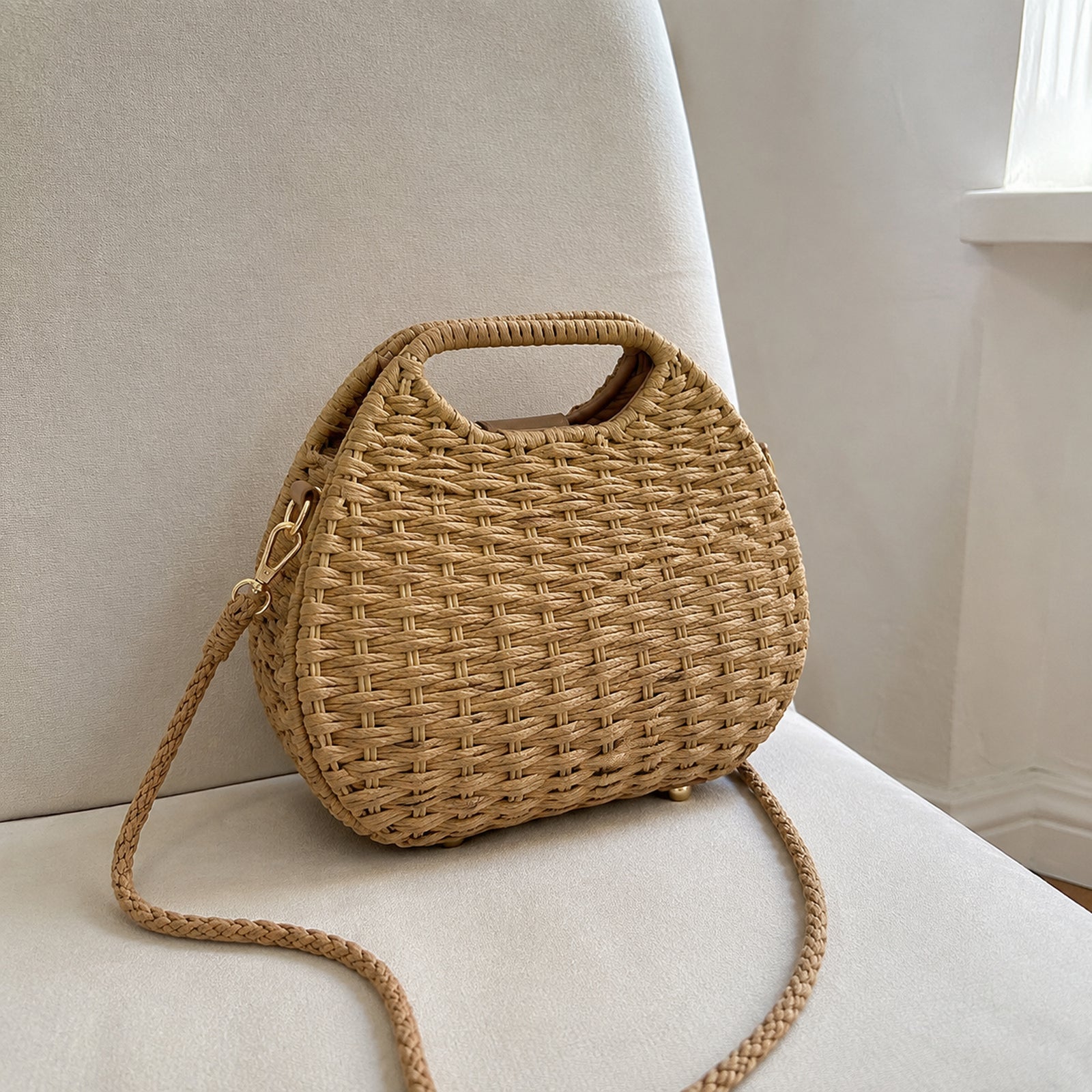 Back and side view of the rounded straw bag with woven handle and braided shoulder strap