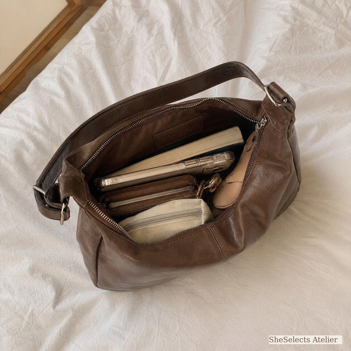 Brown shoulder bag interior shown with realistic daily essentials
