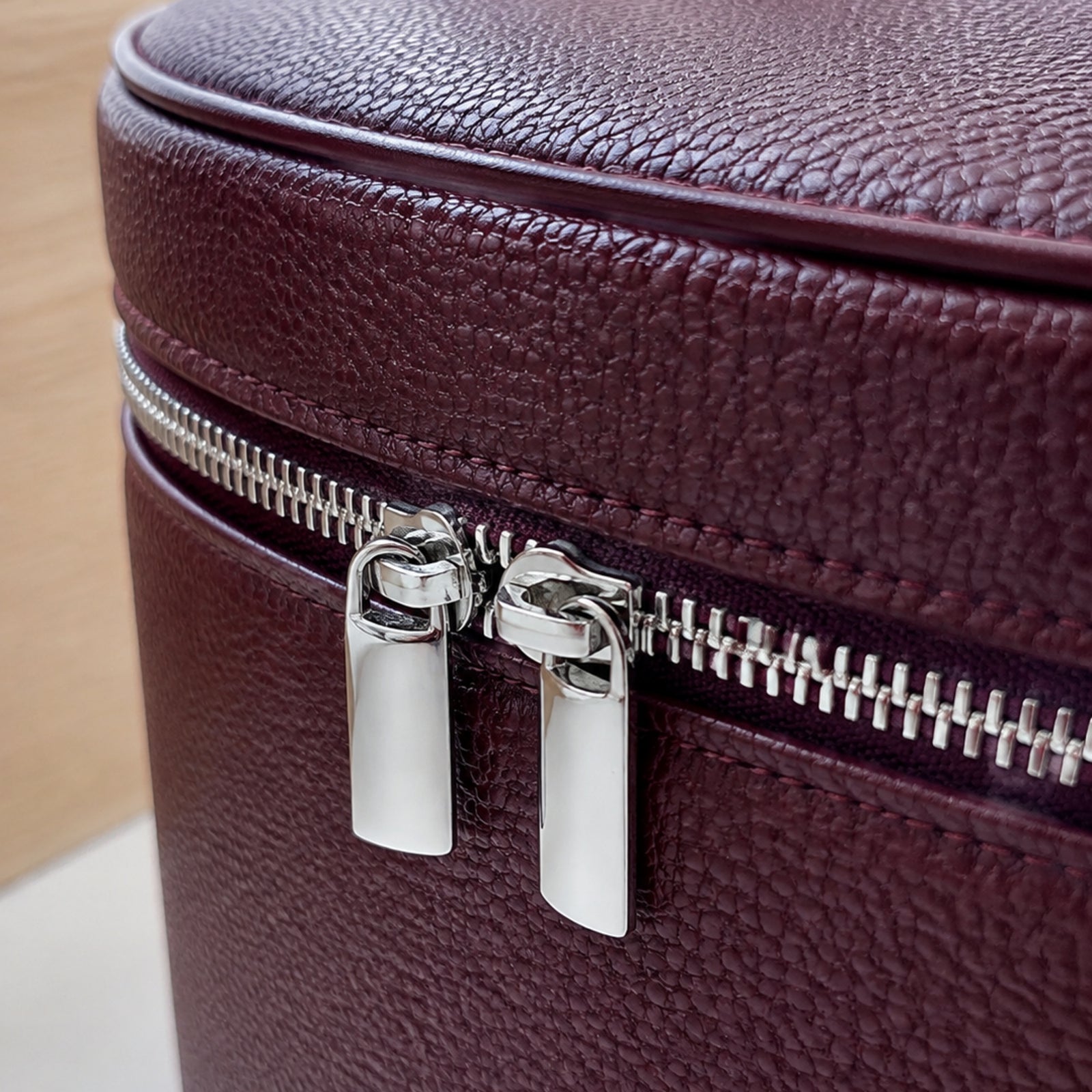 Close view of double silver zipper pulls and wine red lychee-grain Vegan PU Leather