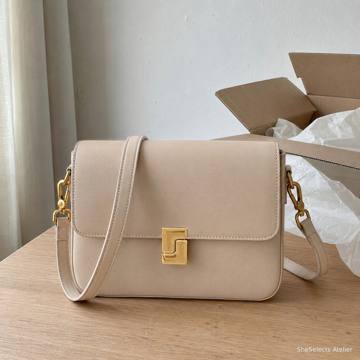 Dark brown leather crossbody bag presented in a cream gift setting