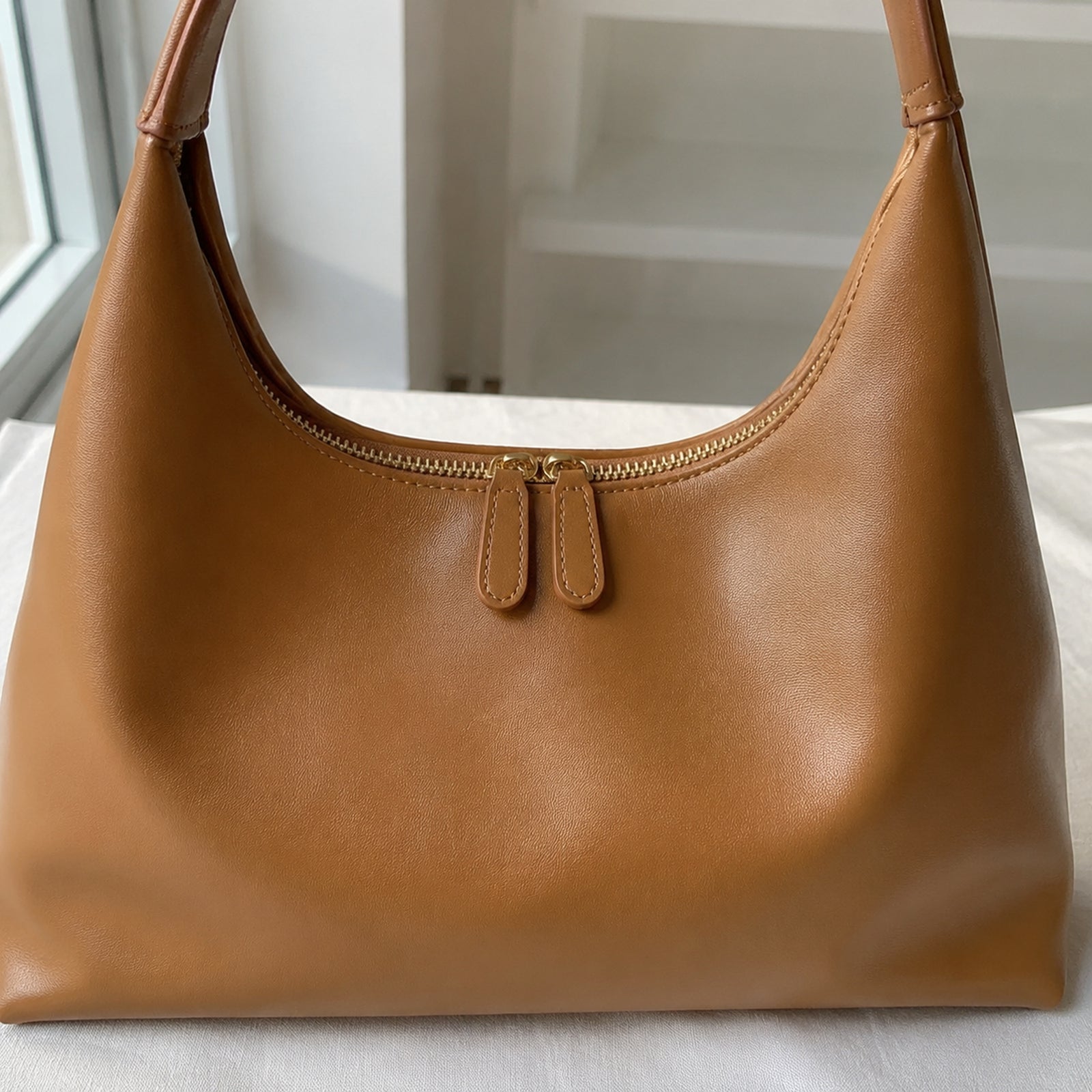 Close-up of Brown Vegan PU Leather texture, stitching, gold zipper, and double pulls