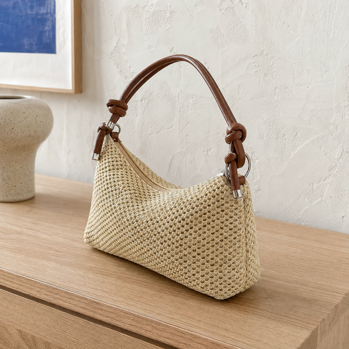 Straw shoulder bag with brown knotted handle in soft window light