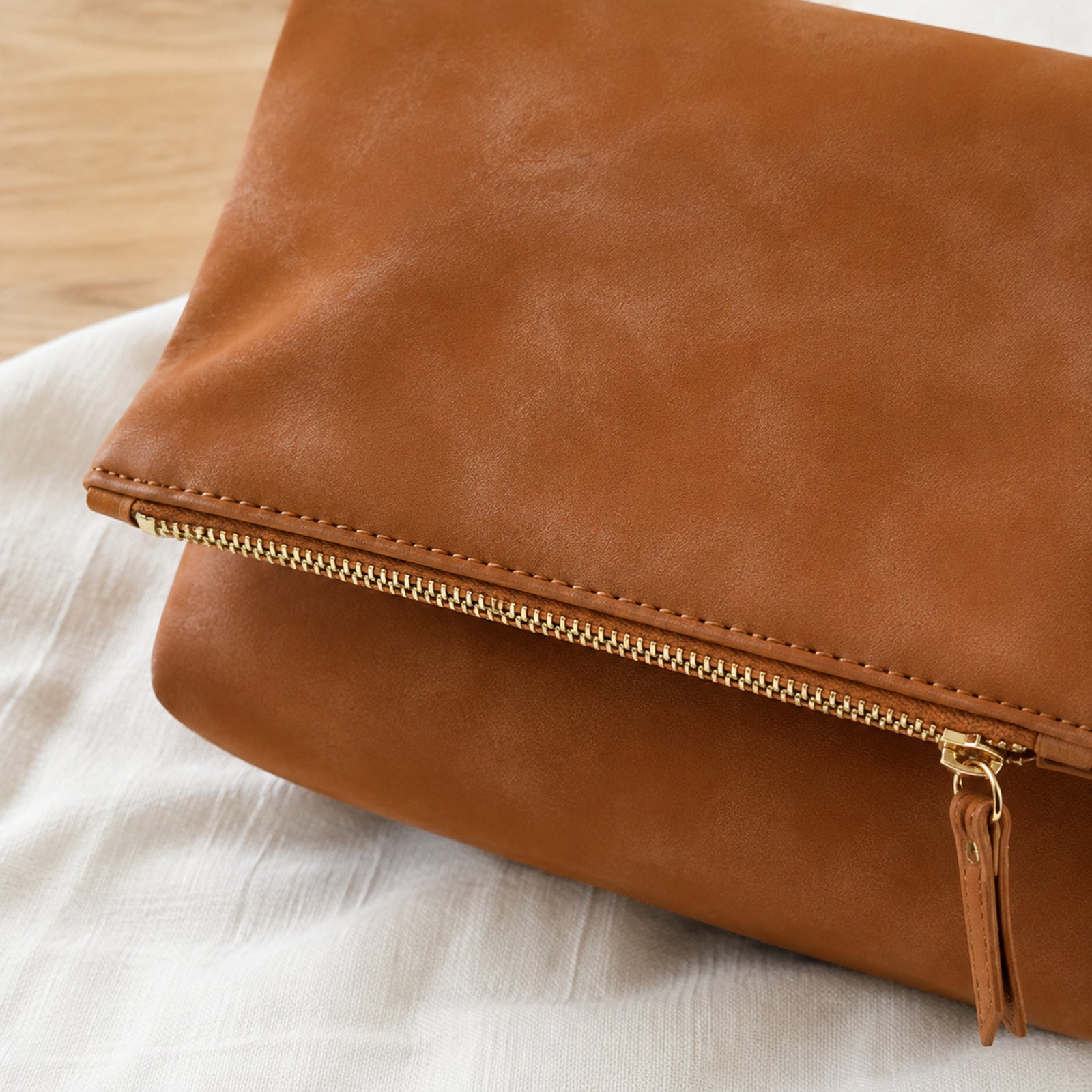 Close view of the gold-tone flap zipper and mottled brown Vegan PU Leather texture