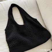 Black hollow knit shoulder bag showing wide integrated handle