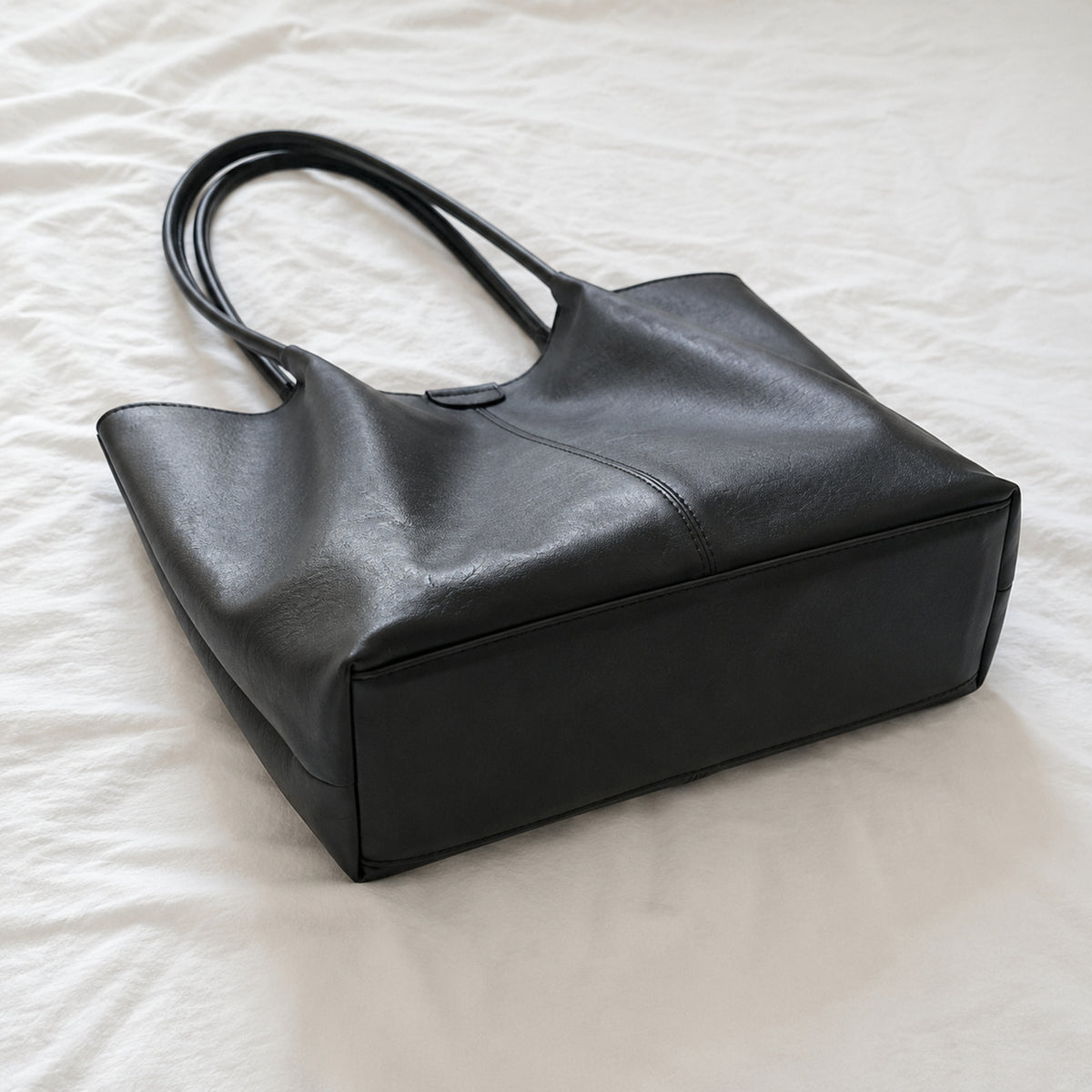 Black large tote shown from the side with its deep gusset and rectangular base