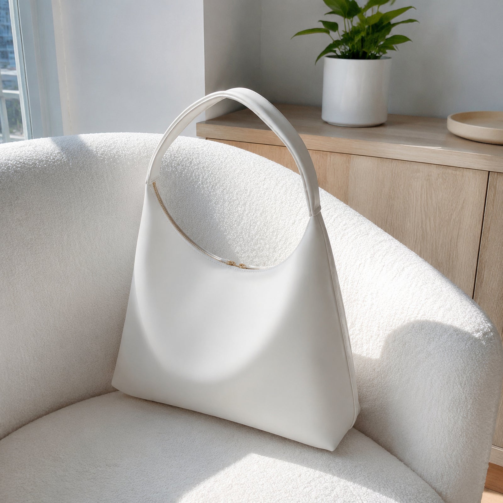 Back and side view of the White pillow-shaped shoulder bag on a white boucle chair