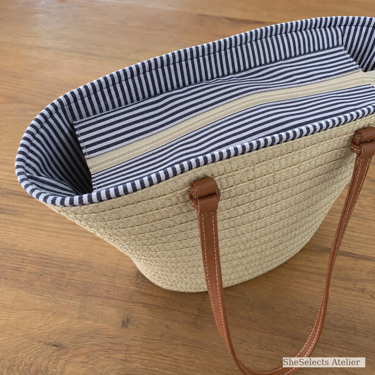 Close-up of zipper closure and navy striped lining on straw tote