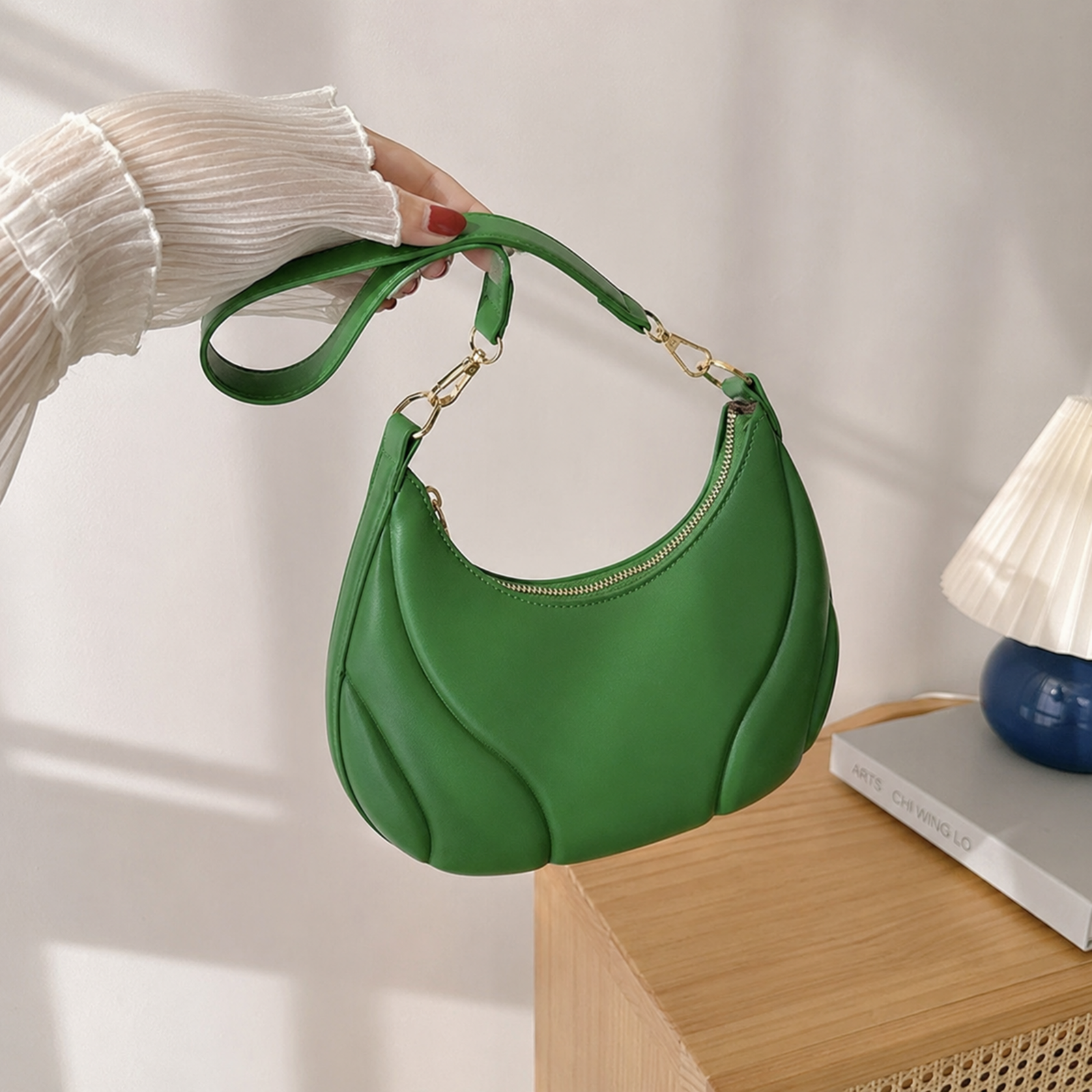 Green crescent purse held by its removable short strap