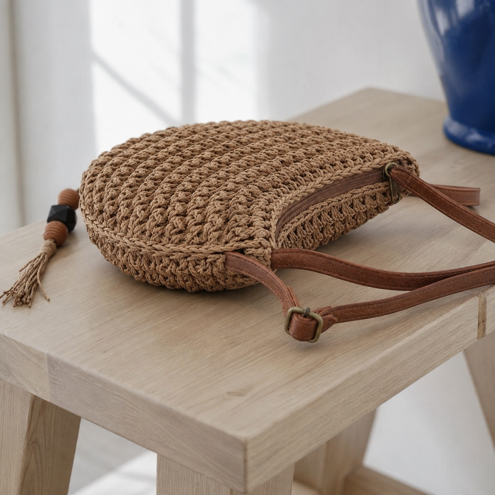 Side view of brown small straw crossbody with adjustable strap