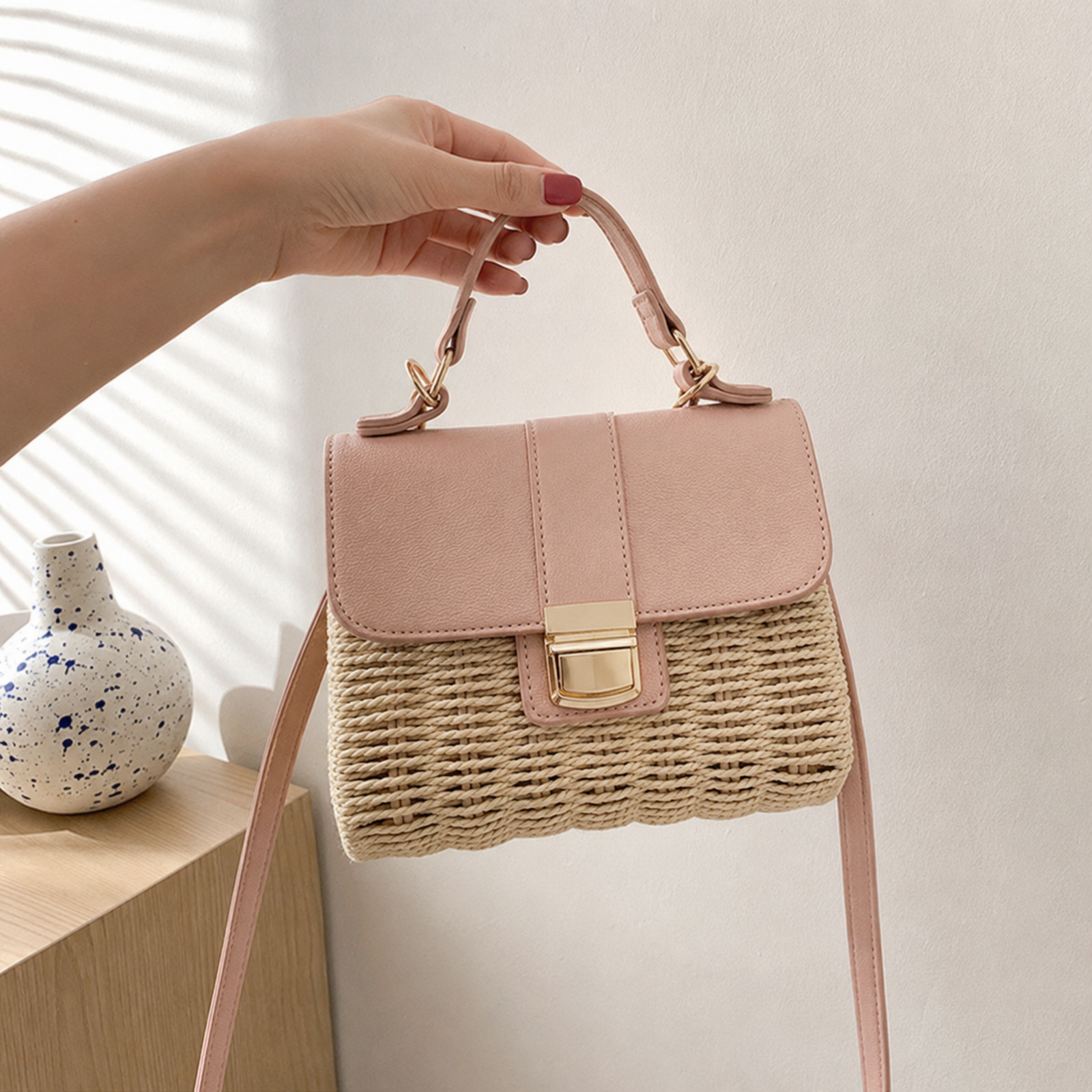 Beige structured straw handbag held by the top handle