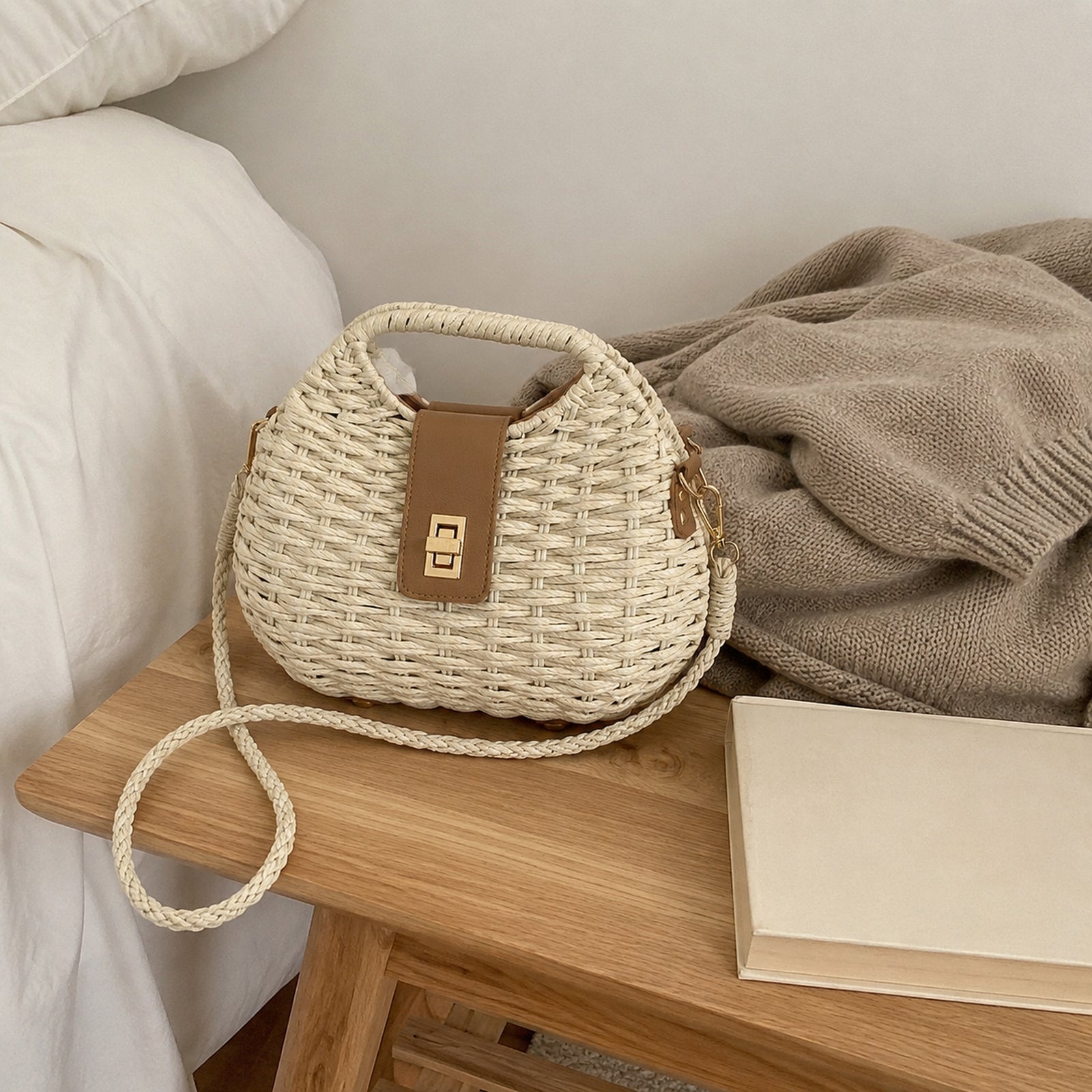 Off White rounded straw shoulder bag beside a neutral knit cardigan in a bright bedroom
