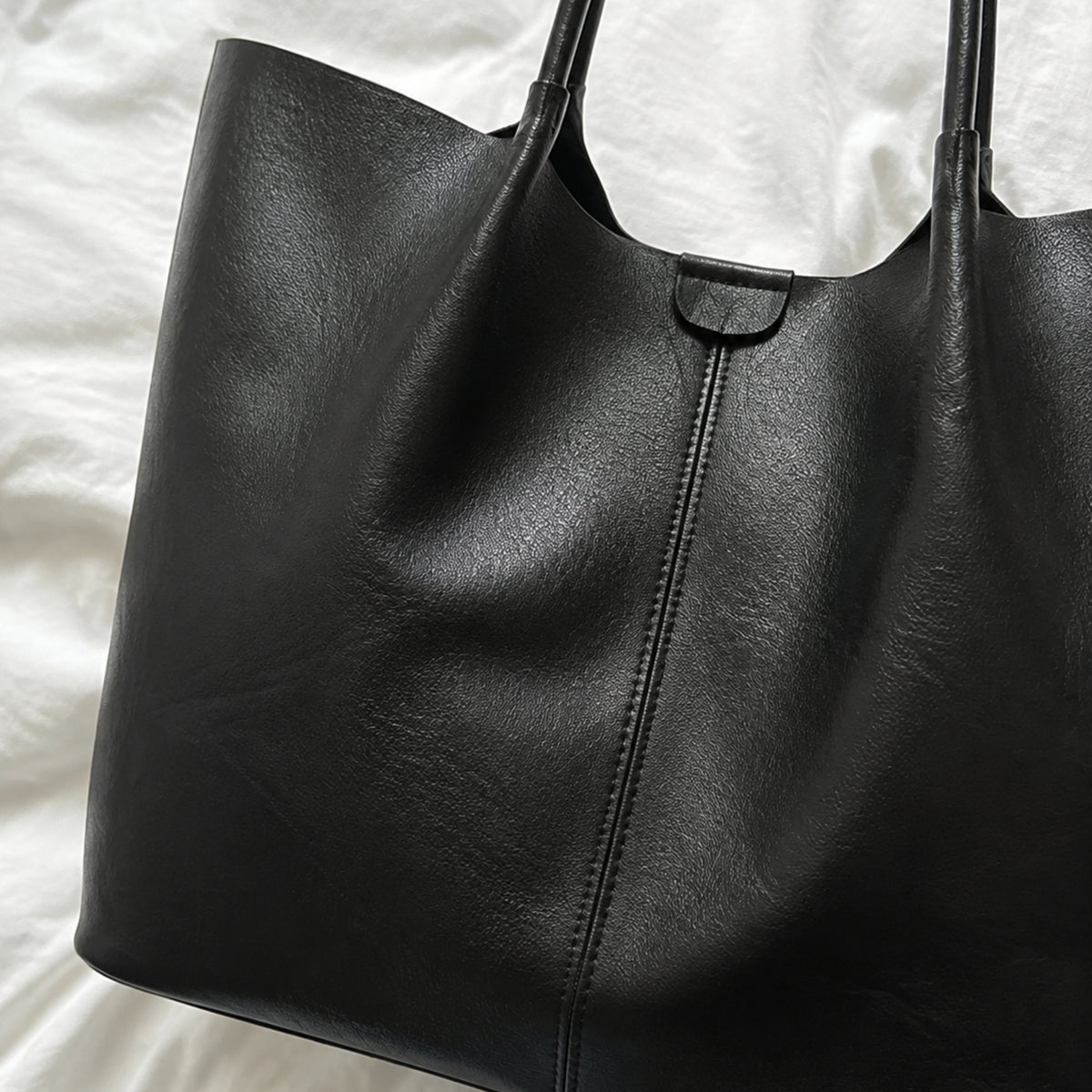 Close view of black Vegan PU Leather texture, center seam, and natural folds