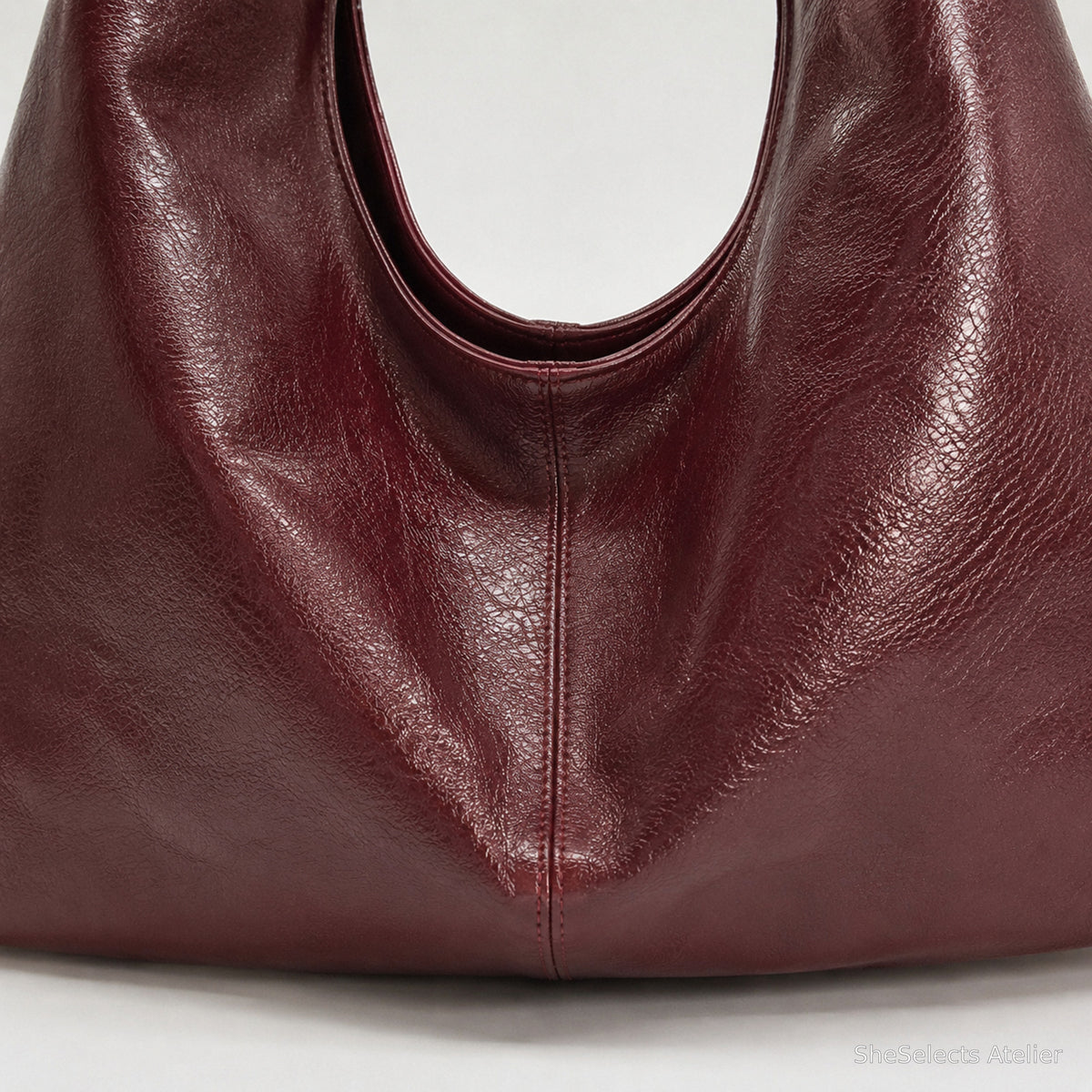 Close view of the wine red glossy vegan leather texture and center seam
