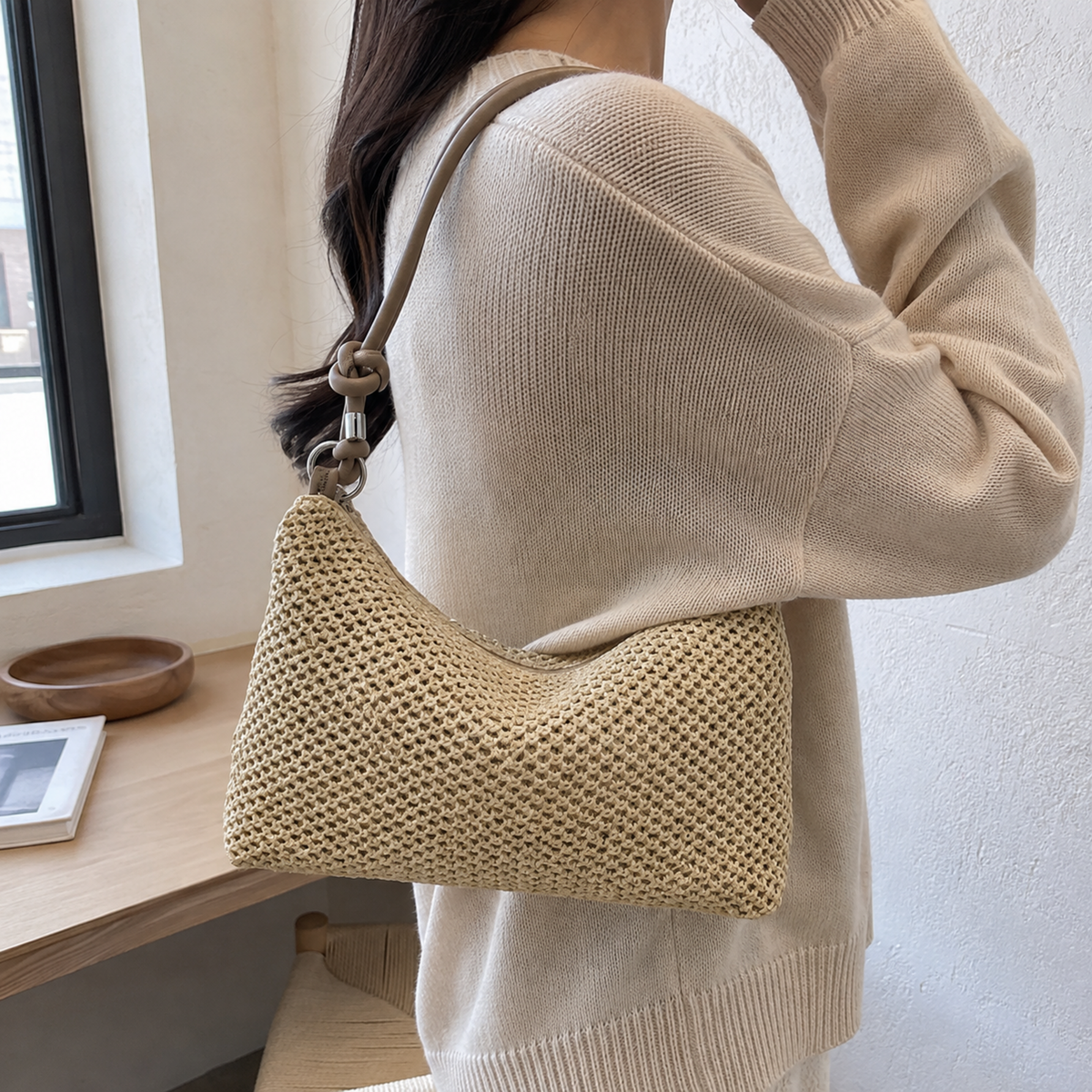 Woven straw hobo with black handle worn on the shoulder
