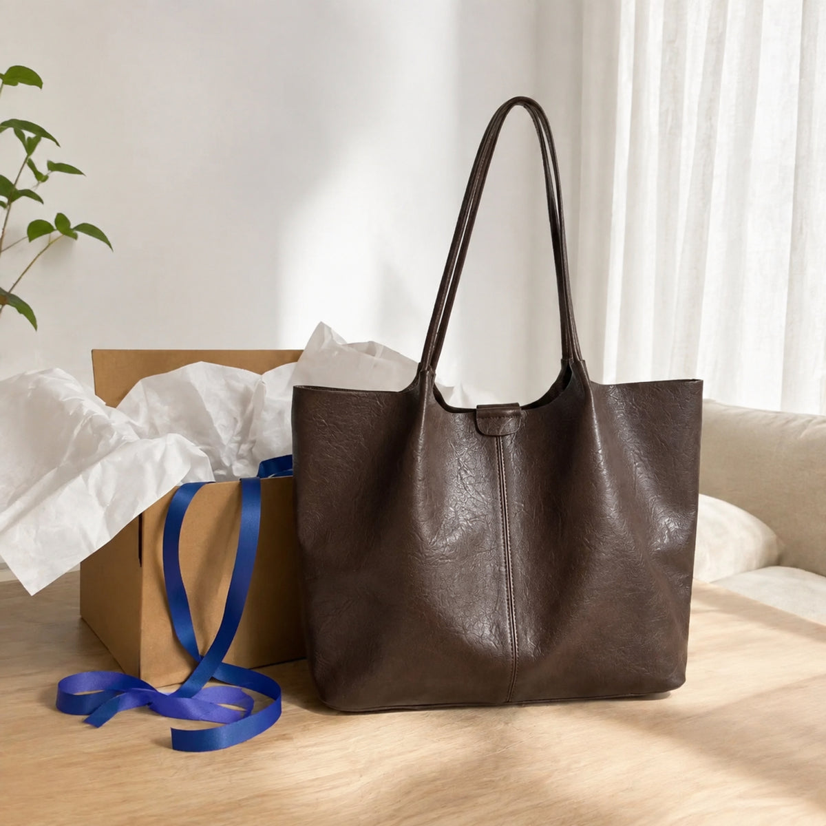 Coffee brown large shoulder tote styled beside kraft gift packaging and blue ribbon