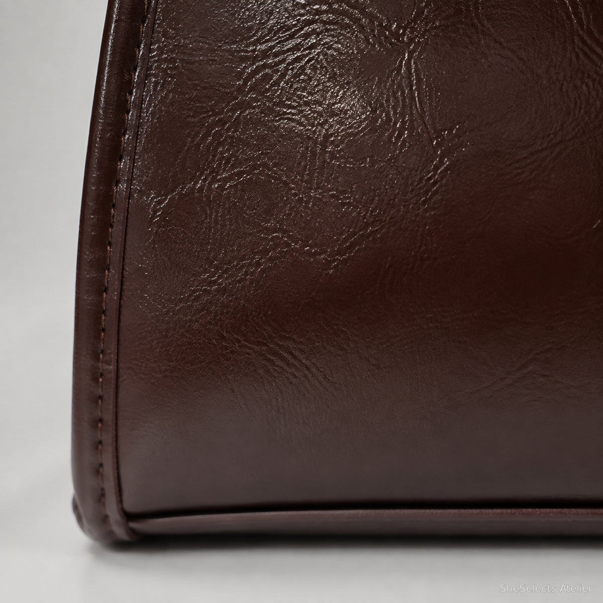 Close-up of brown glossy vegan leather texture and base seam