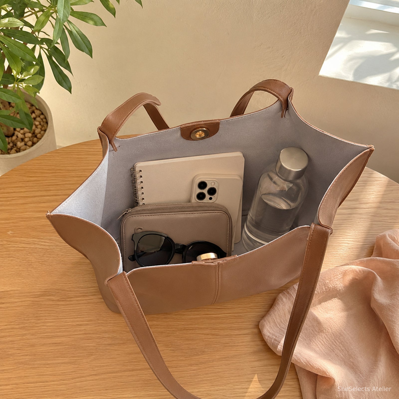 Open brown soft tote showing roomy grey-lined interior with daily essentials