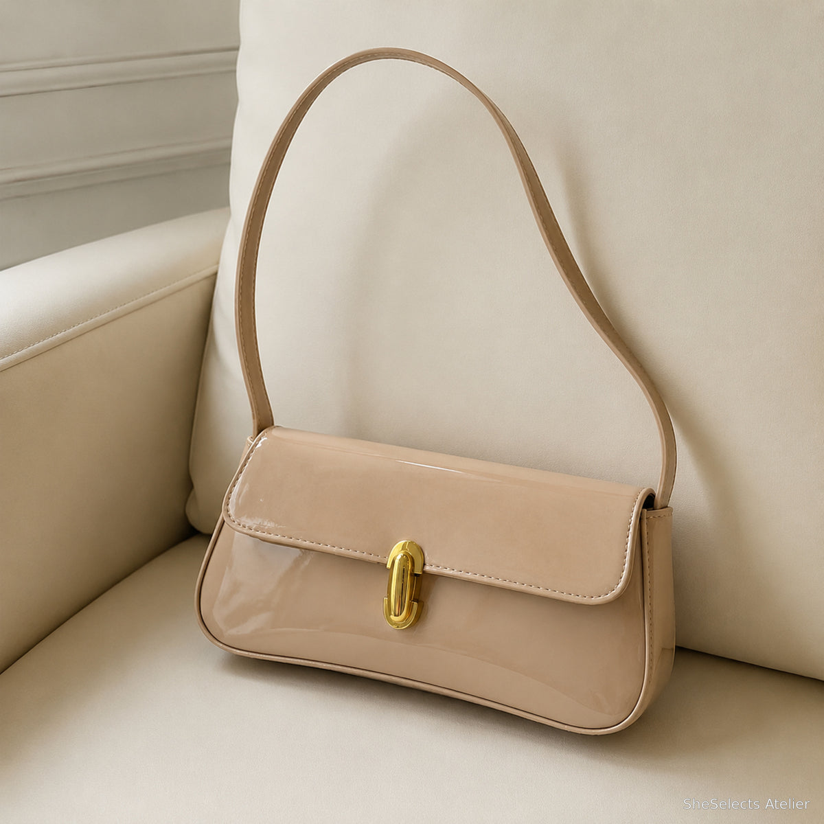 Khaki glossy vegan leather baguette shoulder bag on a cream chair