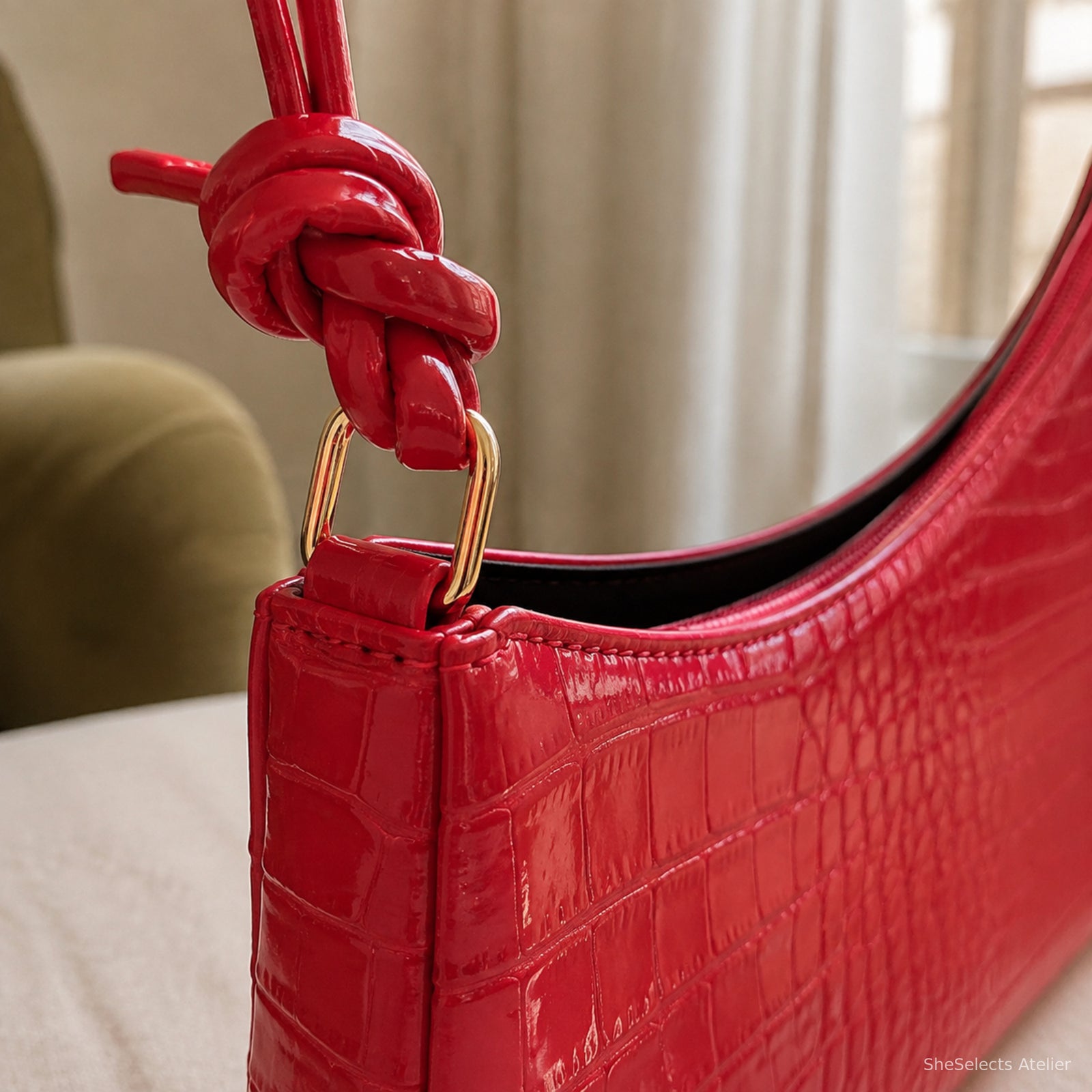 Close-up of bright red croc bag knotted strap and gold connector ring