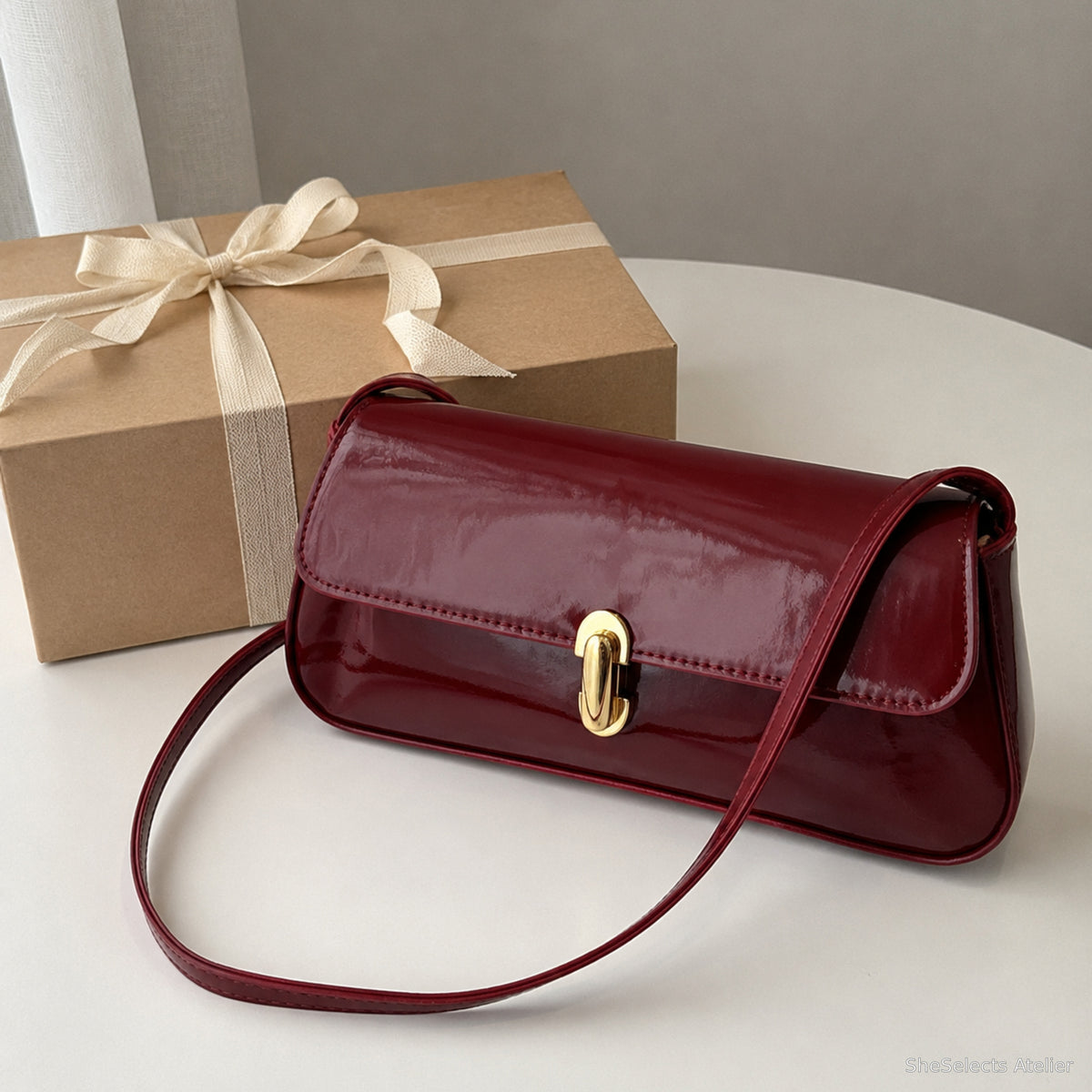 Wine Red glossy baguette bag presented beside a simple gift box