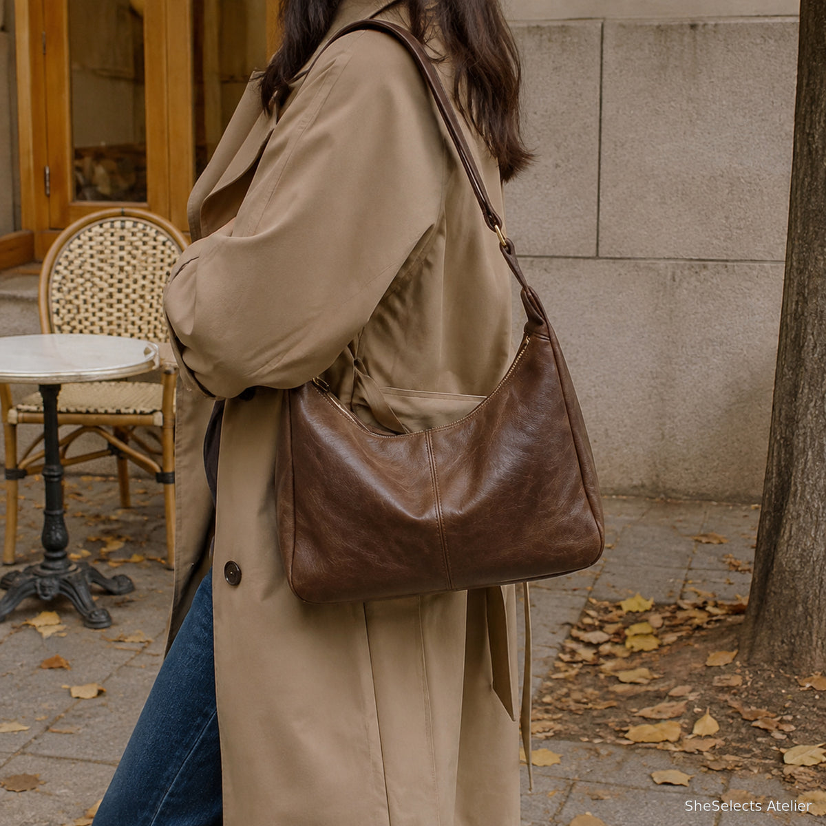 Dark brown vegan leather hobo bag worn with a camel trench coat outdoors