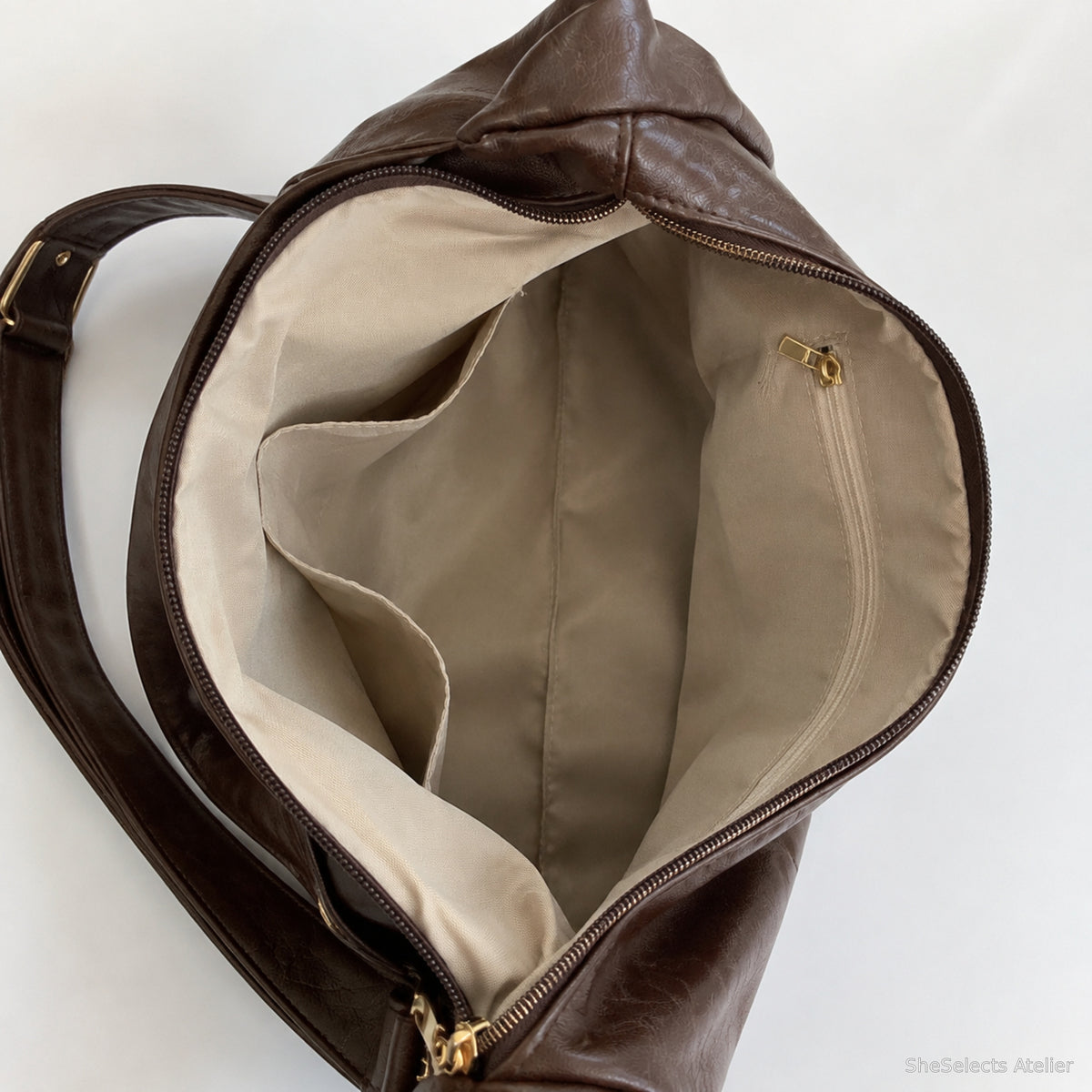 Open dark brown hobo bag showing beige lining, zipper pocket and slip pockets