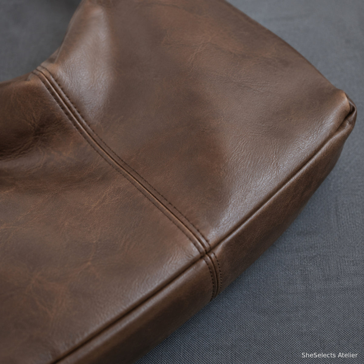 Close view of brown PU vegan leather texture, panel seam and base construction
