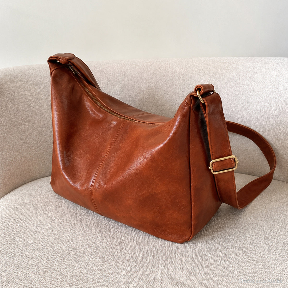 Light brown zipper hobo bag shown from a rear side angle on a beige sofa