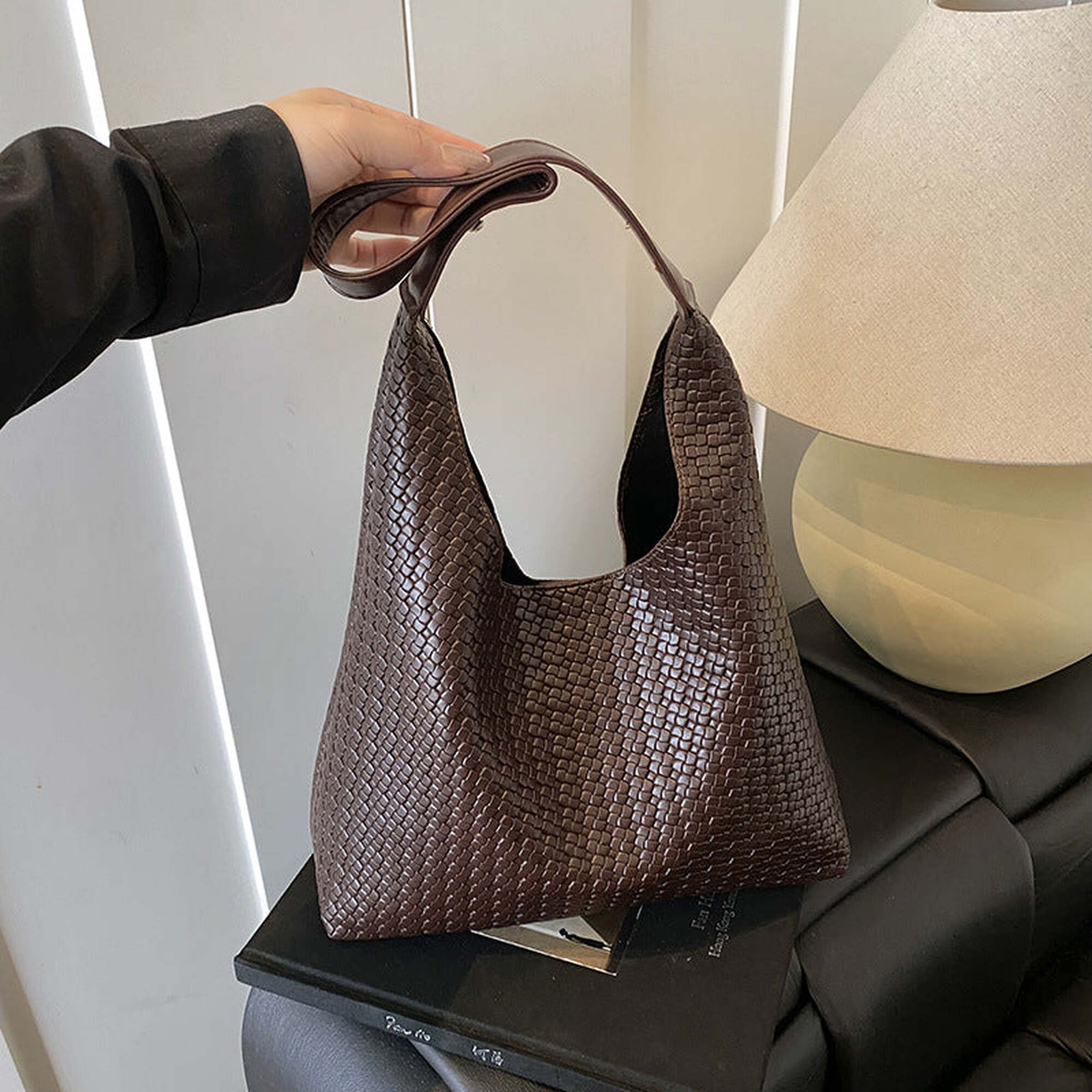 Brown woven vegan leather hobo bag held by its single shoulder strap