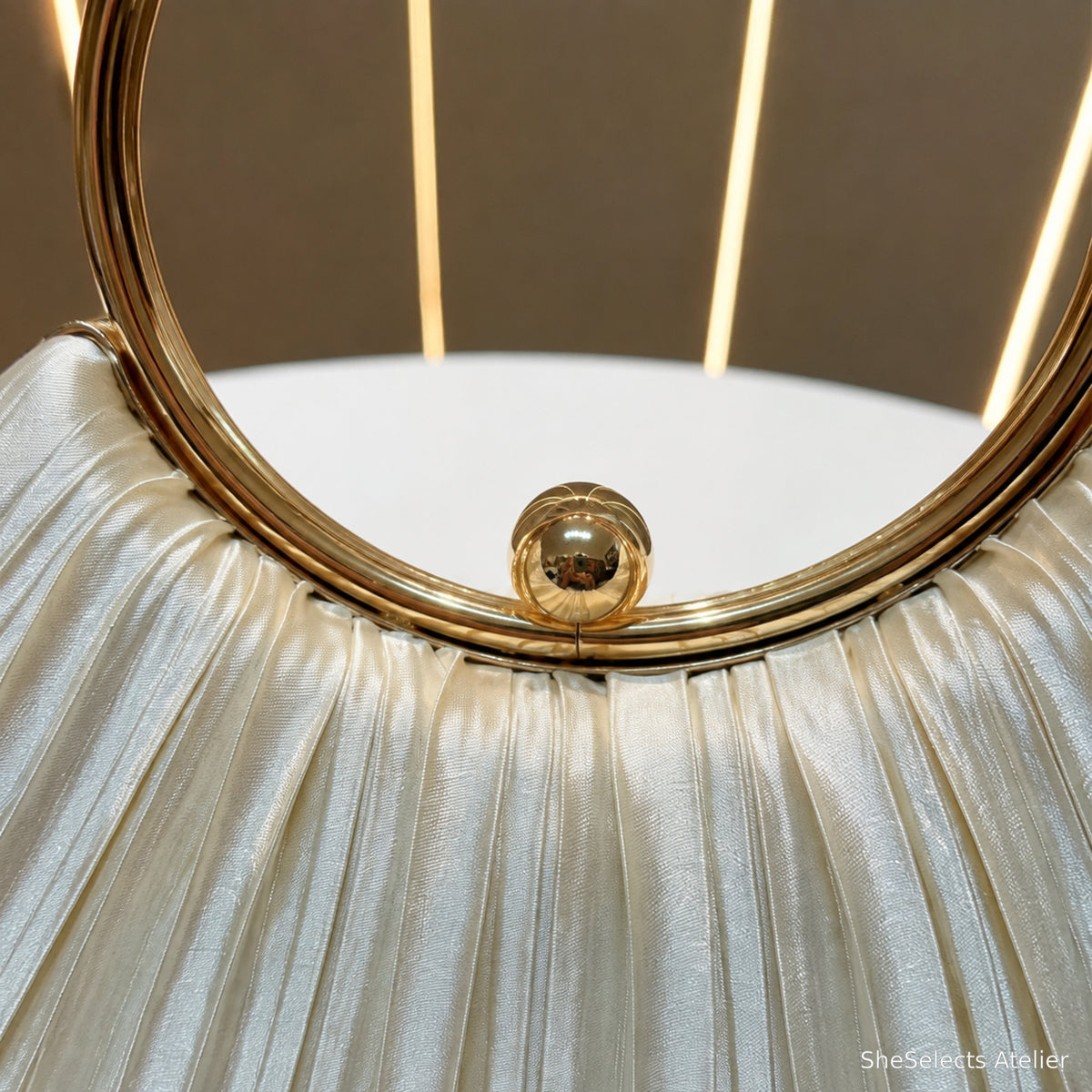 Close view of polished gold ring handle, ball clasp and satin pleating