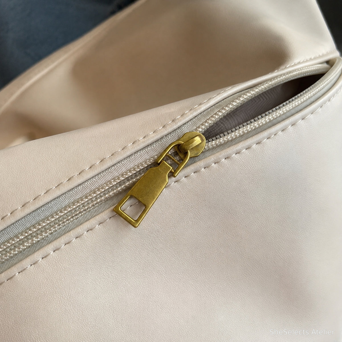 Curved zip top and gold tone pull close up