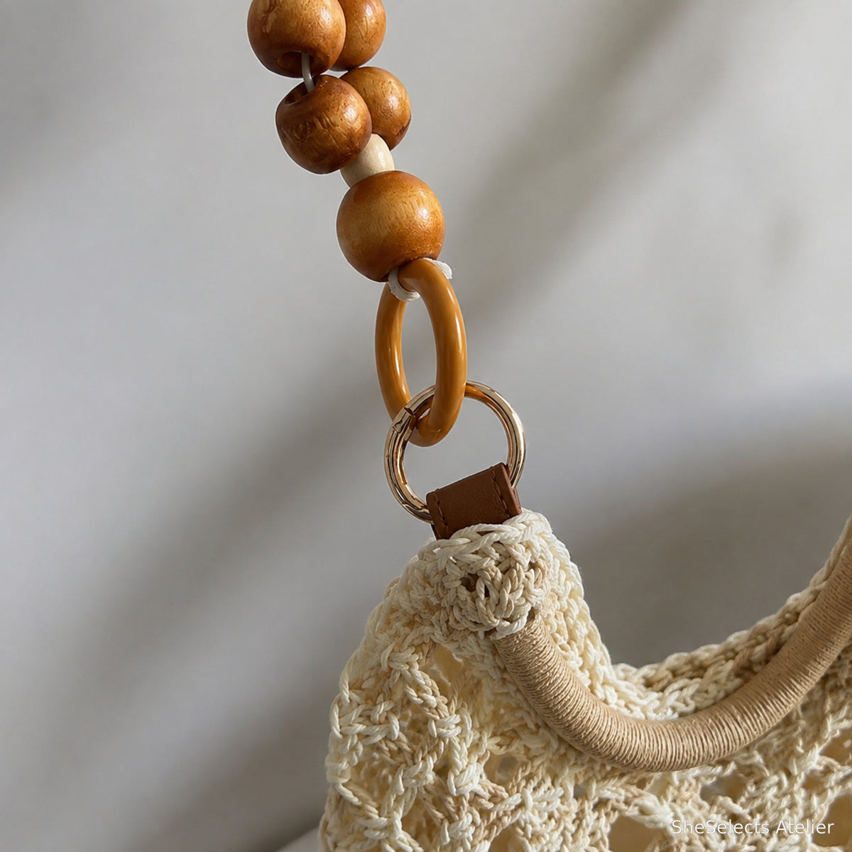 Close-up of rounded bead handle accents, connecting ring and woven attachment